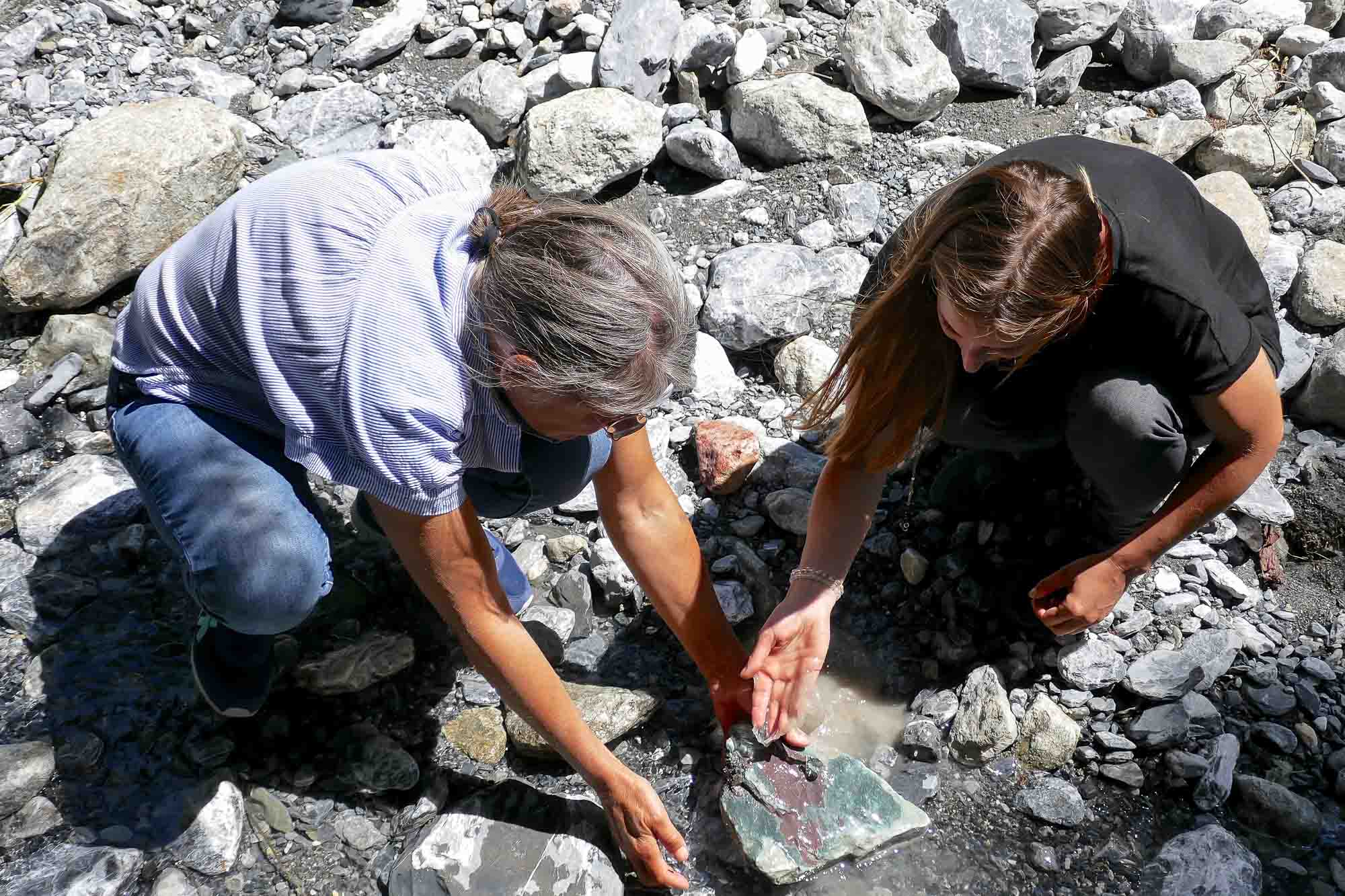 Yolanda Bernhauser und Michaela Wüthrich auf der Suche nach Steinen im Bachbett am Stein mit Wasser ansetzen